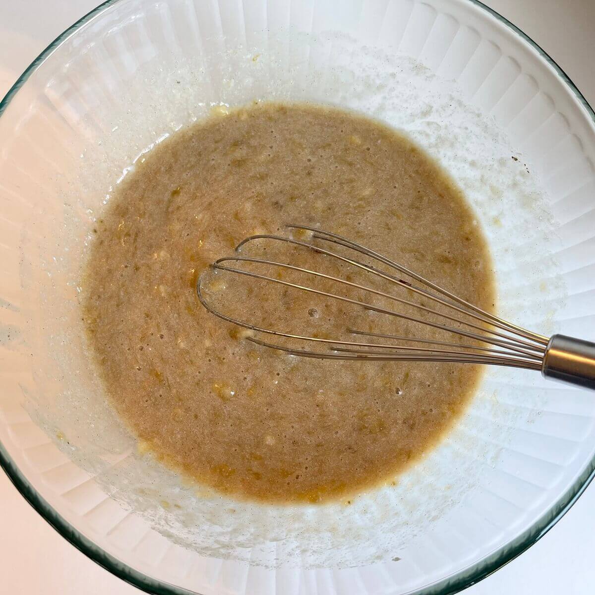 wet ingredients being whisked in a glass bowl.