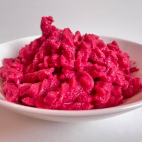A dish of noodles covered in vegan beet pasta sauce.