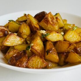 Roasted potatoes piled in a white bowl.