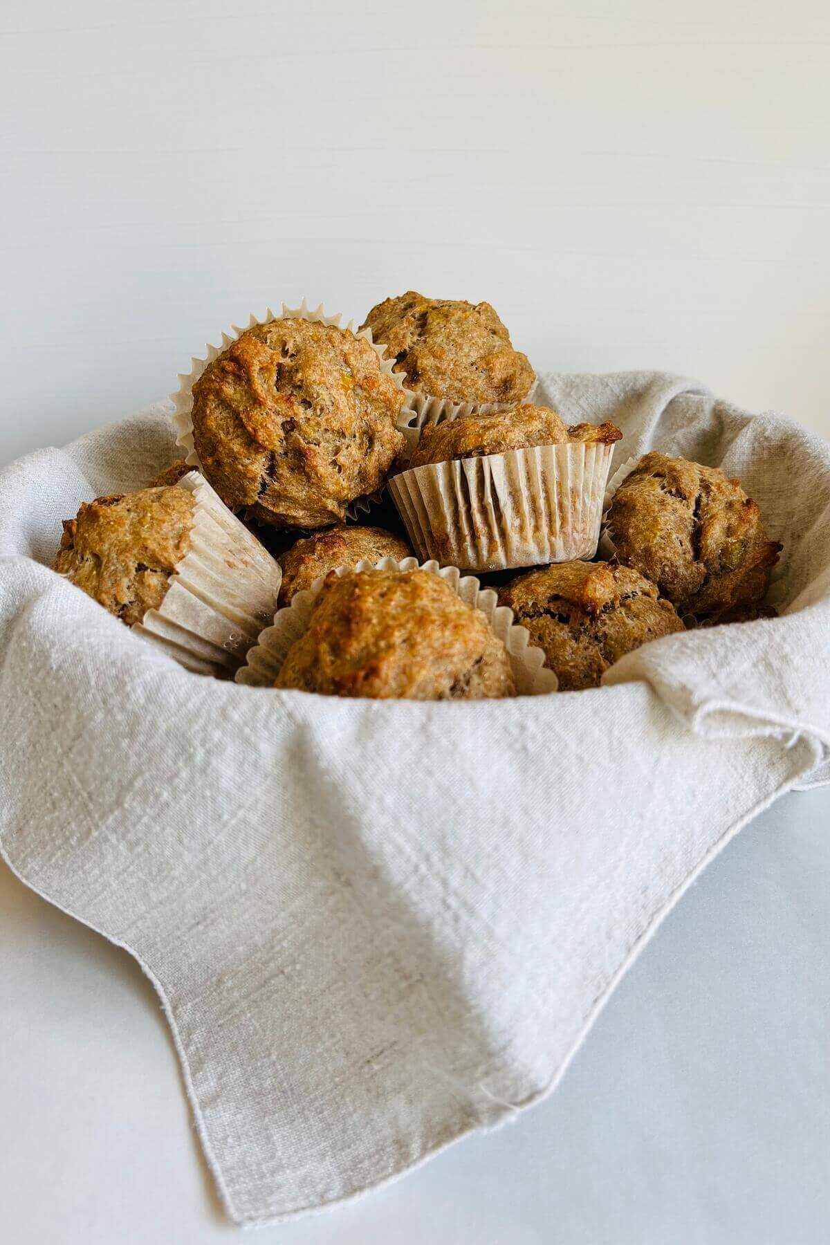 Banana muffins in a basket lined with a beige linen cloth.