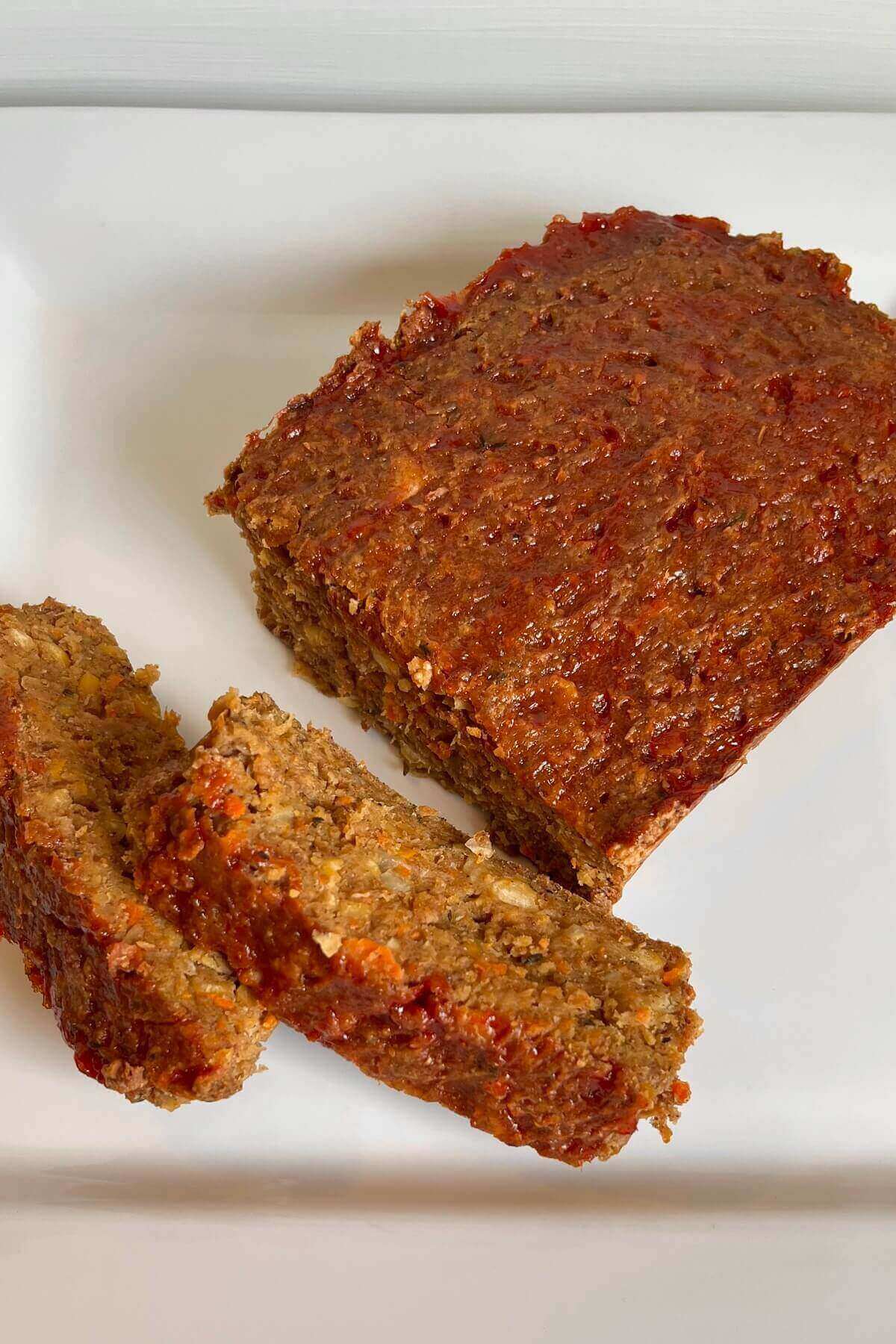 Vegan meatloaf with slices cut on a white plate.