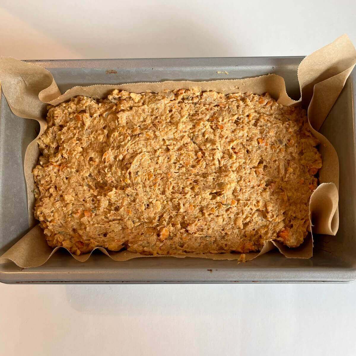 Raw vegetarian meatloaf in a metal pan lined with parchment paper.