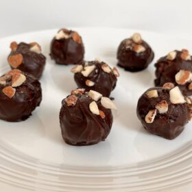 Eight almond butter chocolates with chopped almonds sprinkled on top.