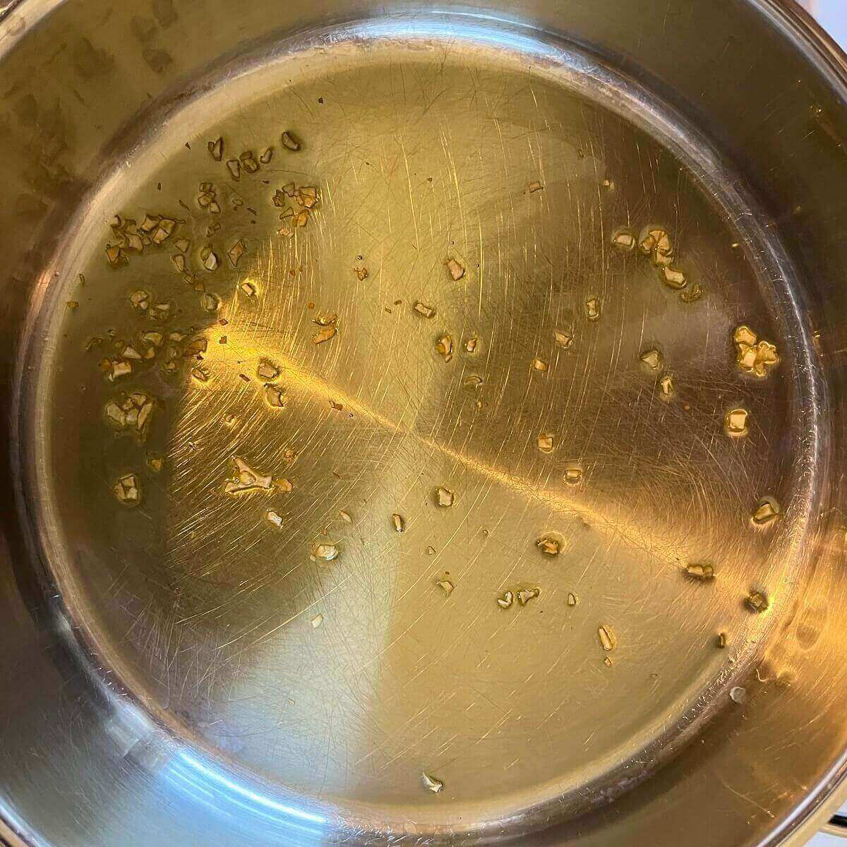 Chopped garlic and olive oil in a metal pan.