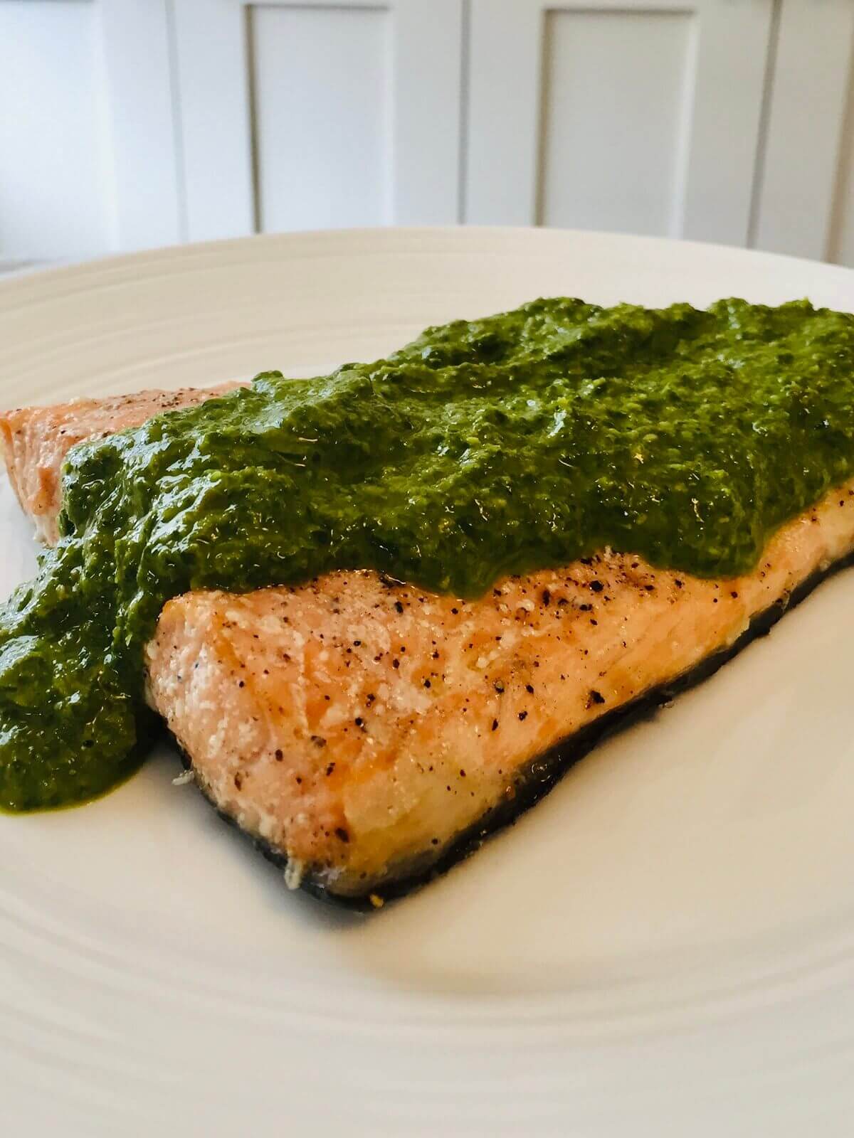 A piece of fish smothered in a green sauce.