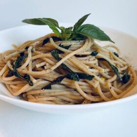 Pasta with basil in a white bowl.
