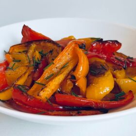 Roasted red, orange, and yellow pepper slices in a bowl.