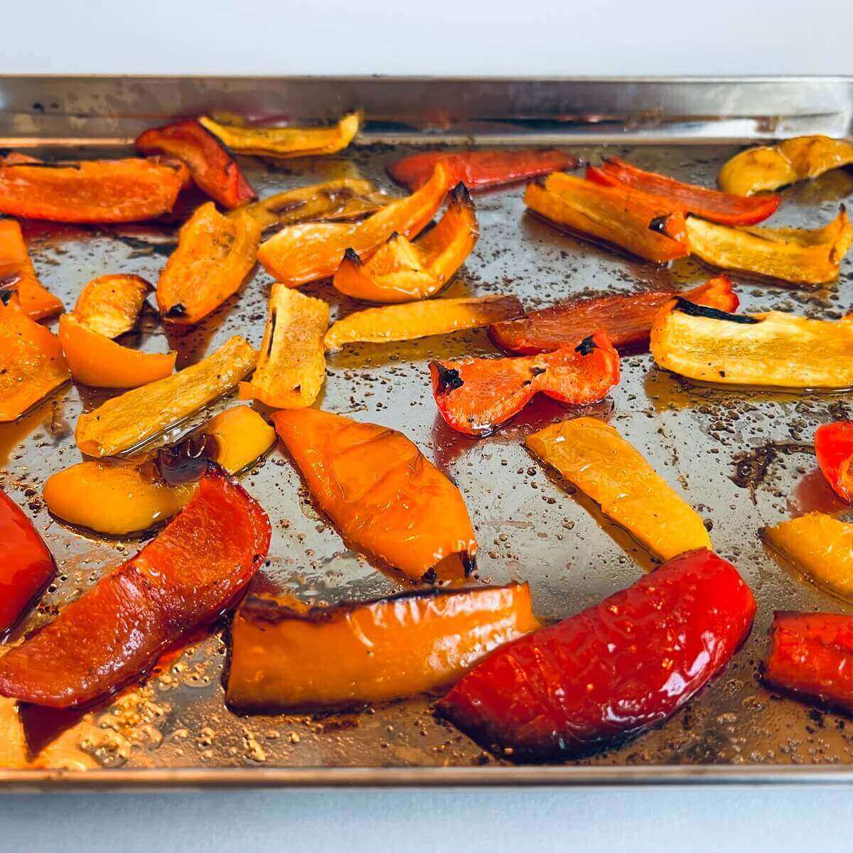 Roasted bell peppers on a metal sheet pan.