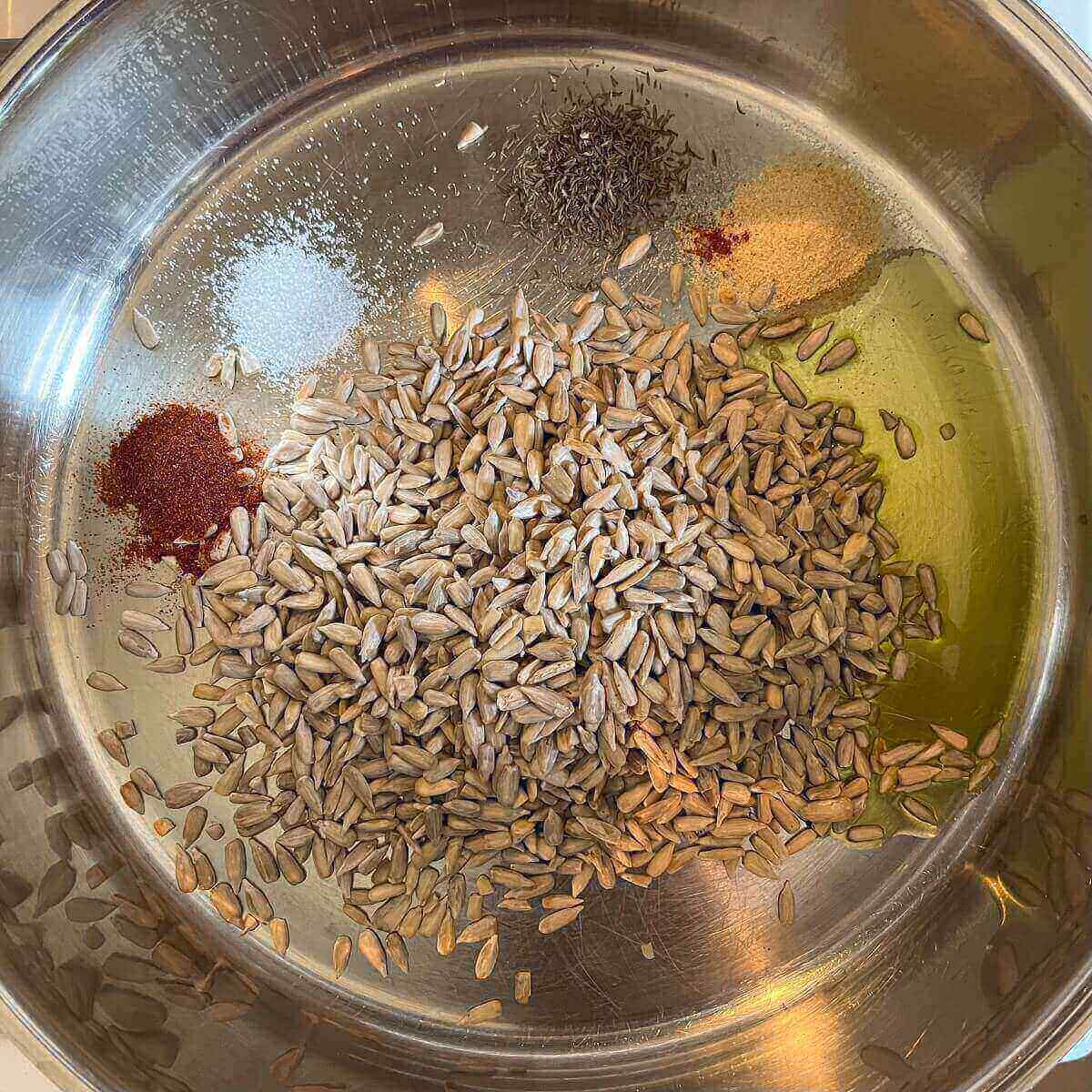 Sunflower seeds, oil, and spices in a metal pan.