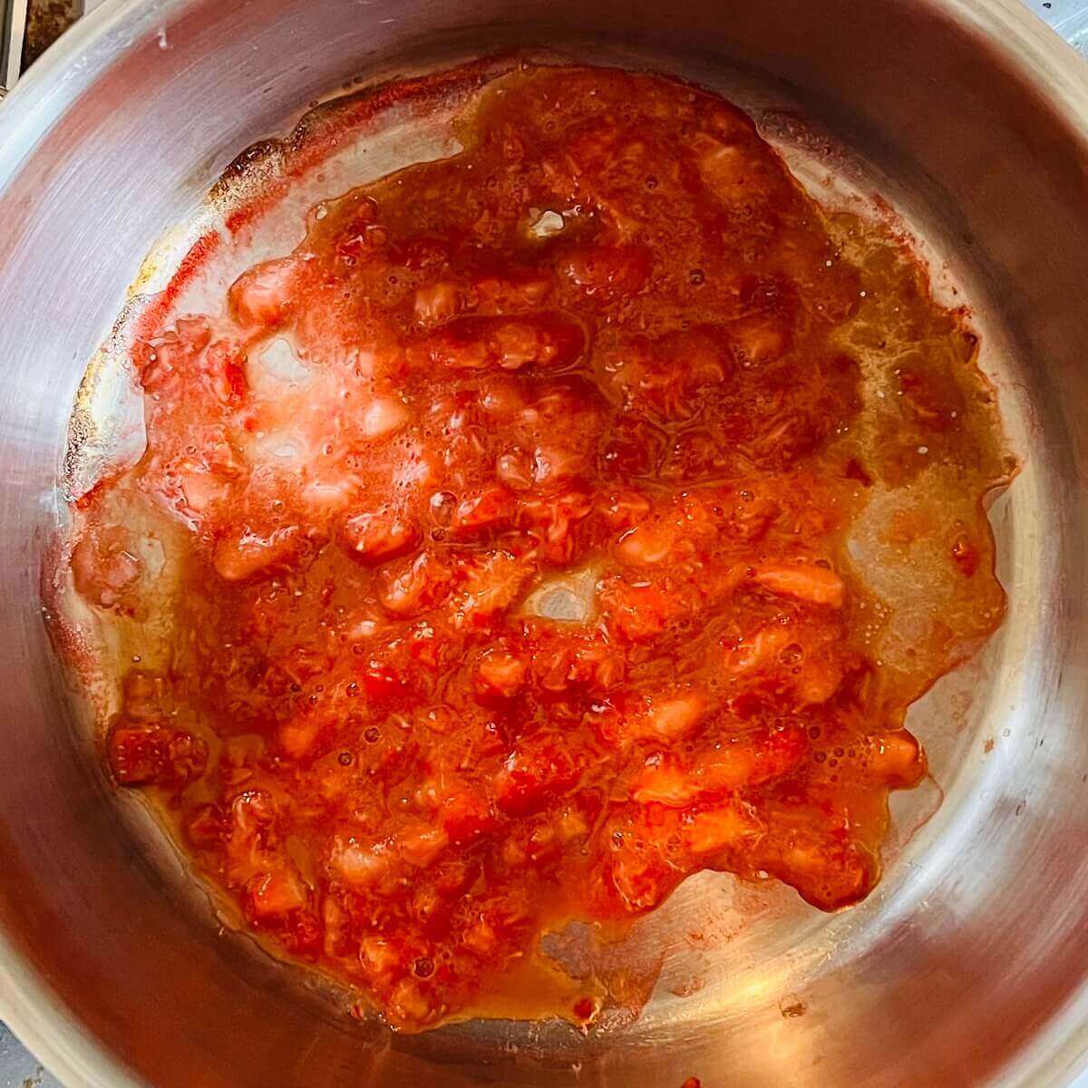 Mashed strawberries in a metal pot.