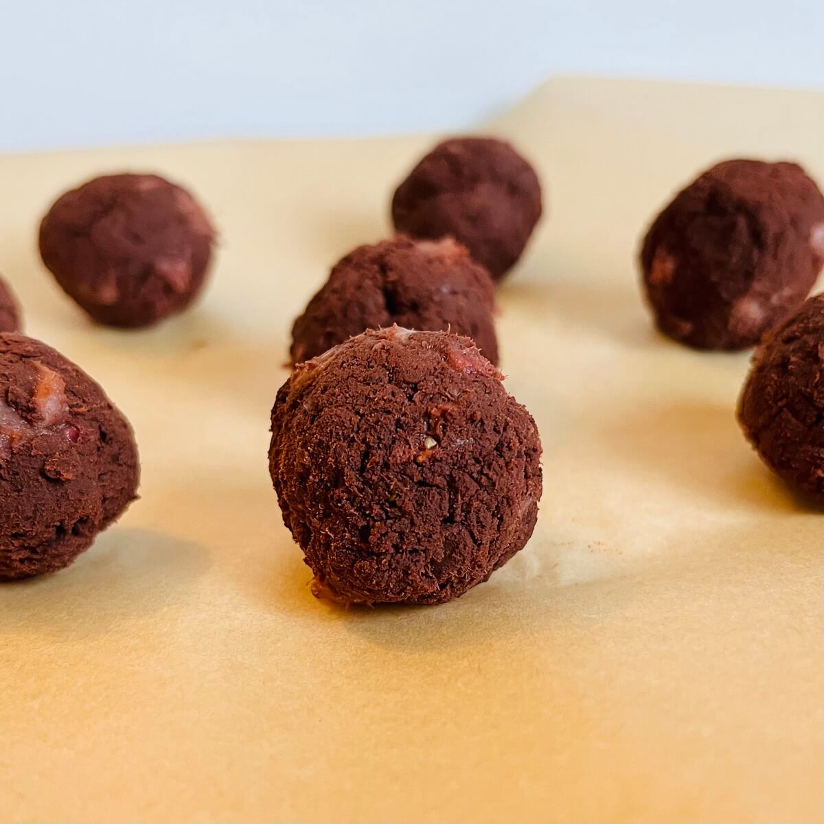 Strawberry chocolate balls on a piece of parchment paper.