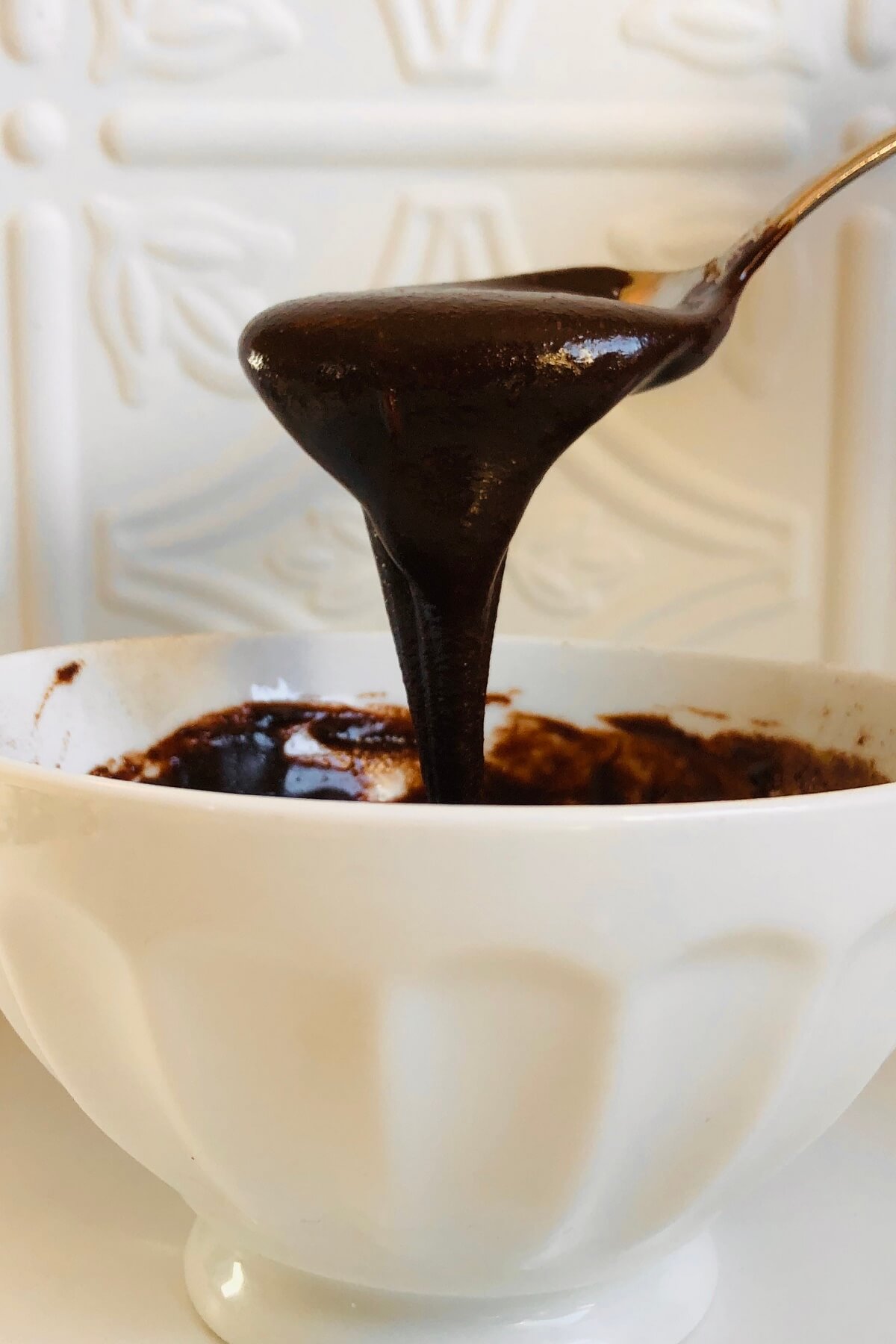 Tahini icing dripping off a metal spoon.