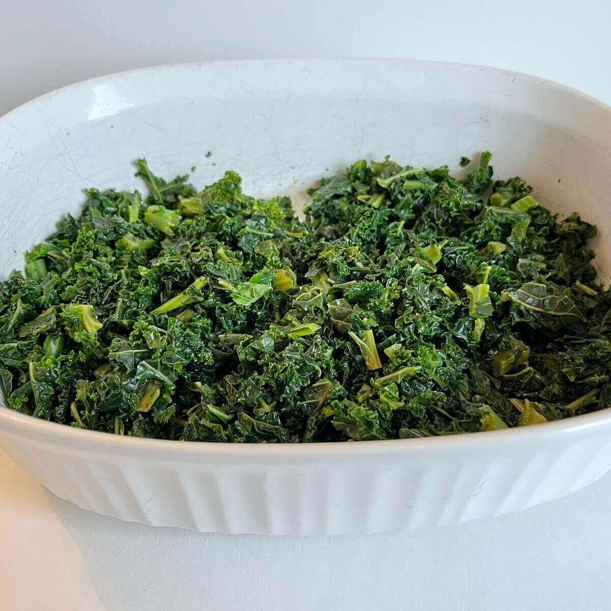 Cooked chopped kale in a white baking dish.