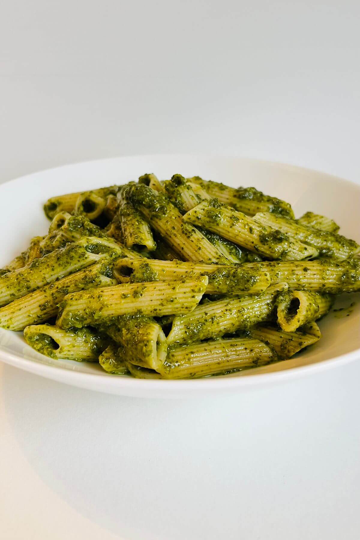 A bowl of penne pasta in a green sauce.