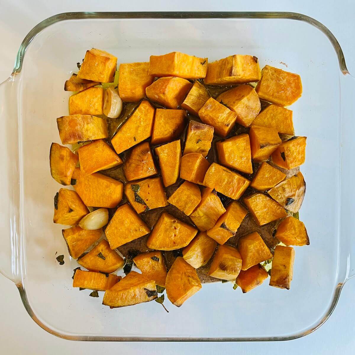 Roasted sweet potato chunks in a glass baking dish.