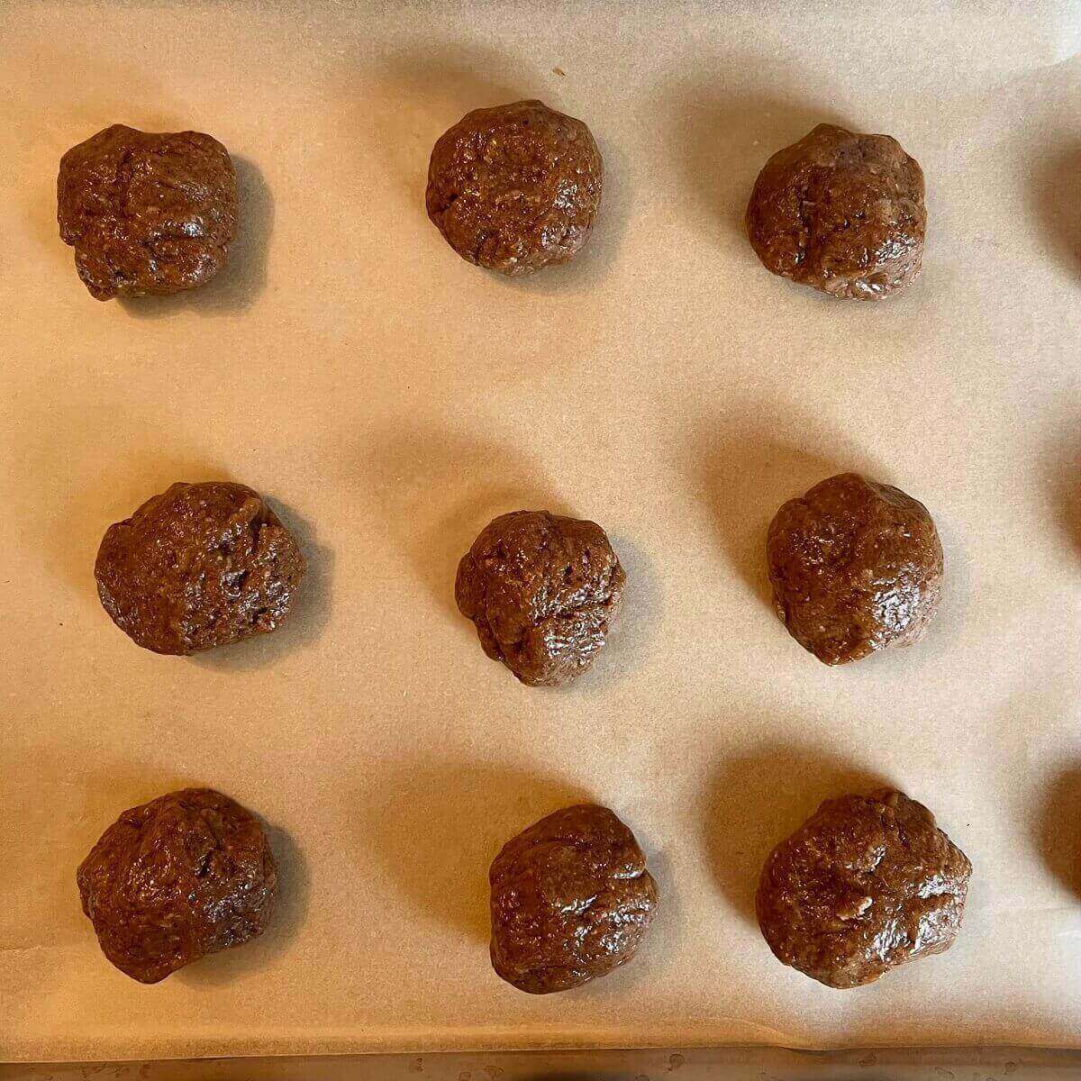 Raw cookie dough balls on a baking sheet lined with parchment paper.