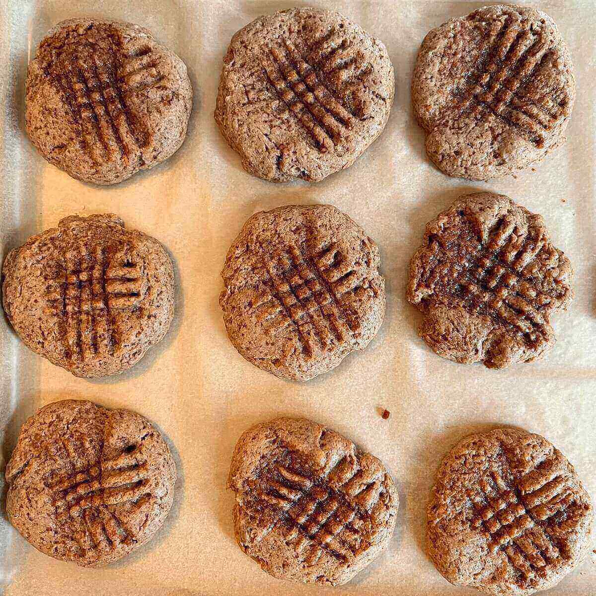 Nine cookies on a sheet pan lined with parchment paper.