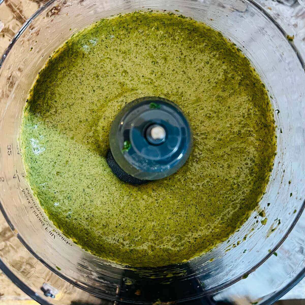 A blended green mixture in a food processor.