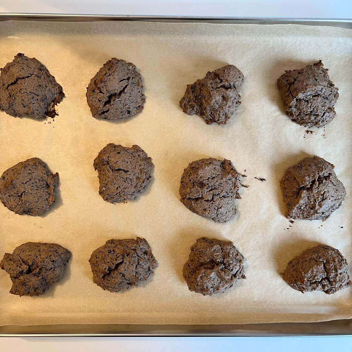 Twelve freshly baked cookies on a sheet pan lined with parchment paper.