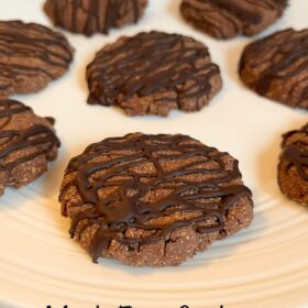 Chocolate drizzled cookies on a white plate.