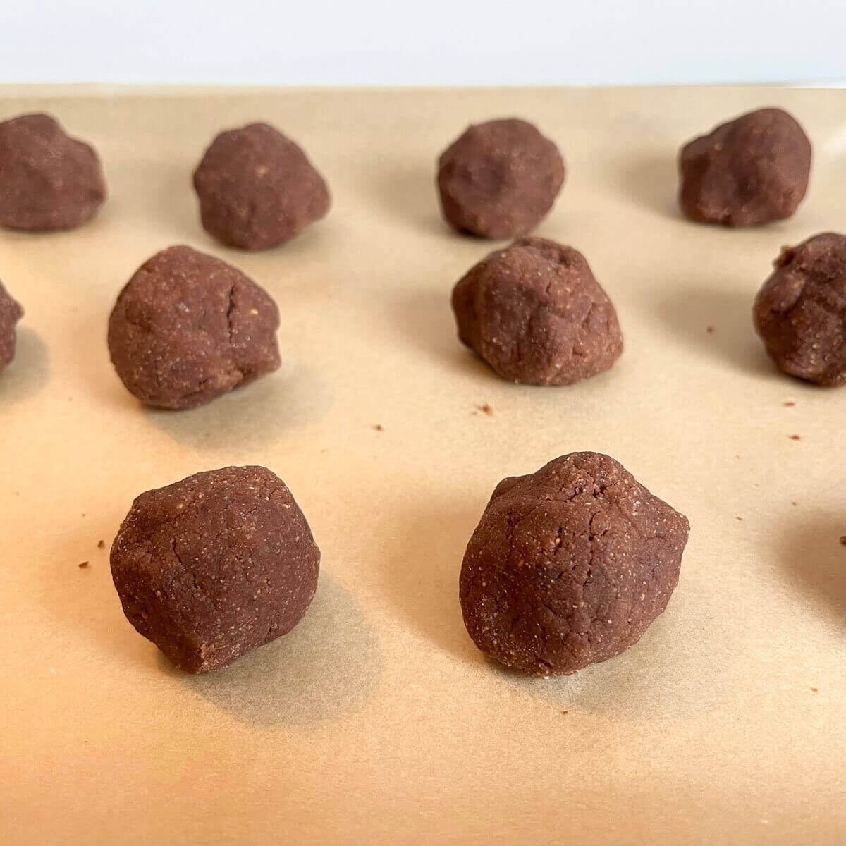 Raw cookie balls on a sheet pan lined with parchment paper.