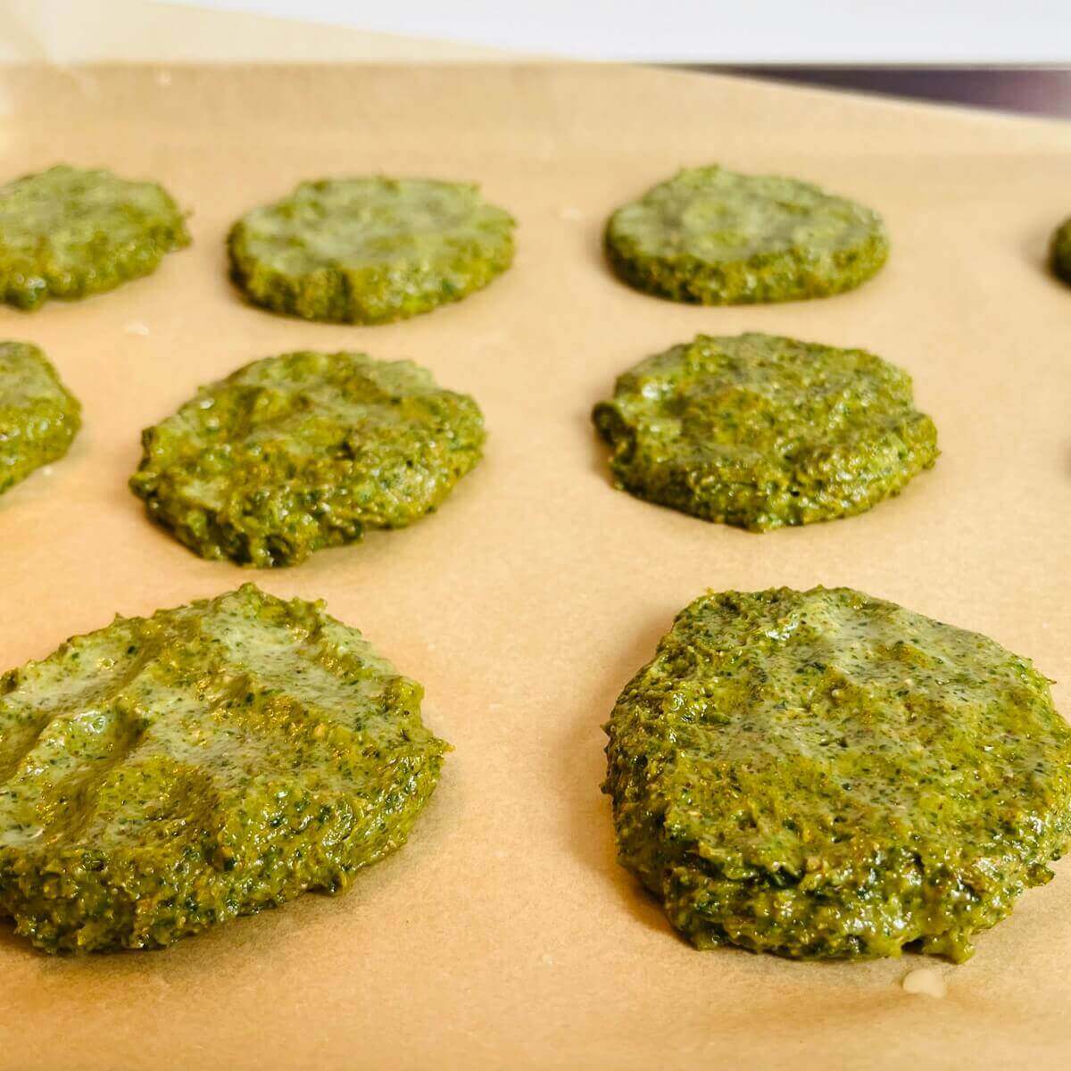 Raw green cookies on a sheet pan lined with parchment paper.