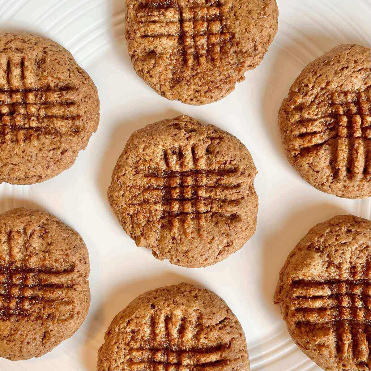 Seven vegan almond butter cookies on a white plate.