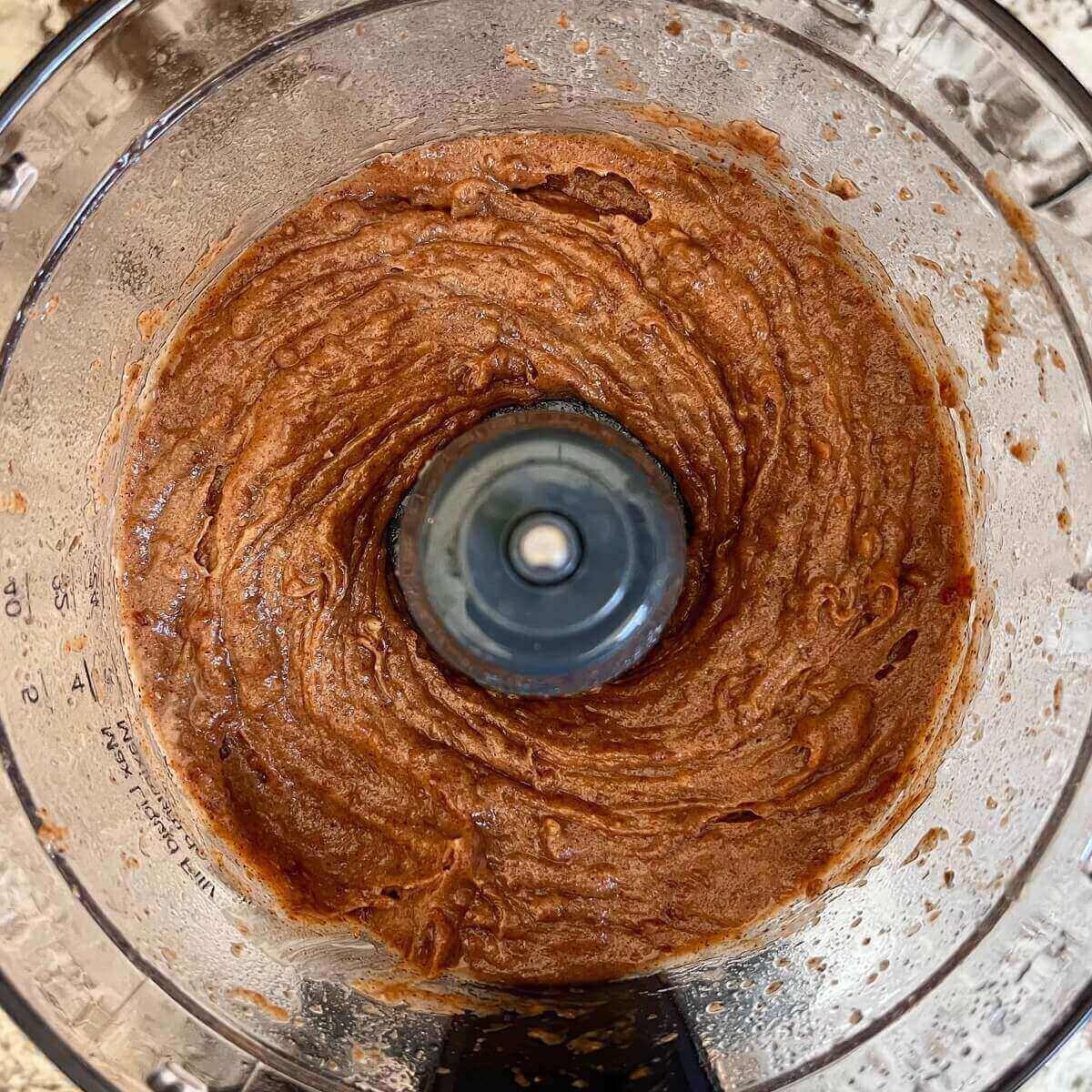 A thick, brown, blended mixture in a food processor.