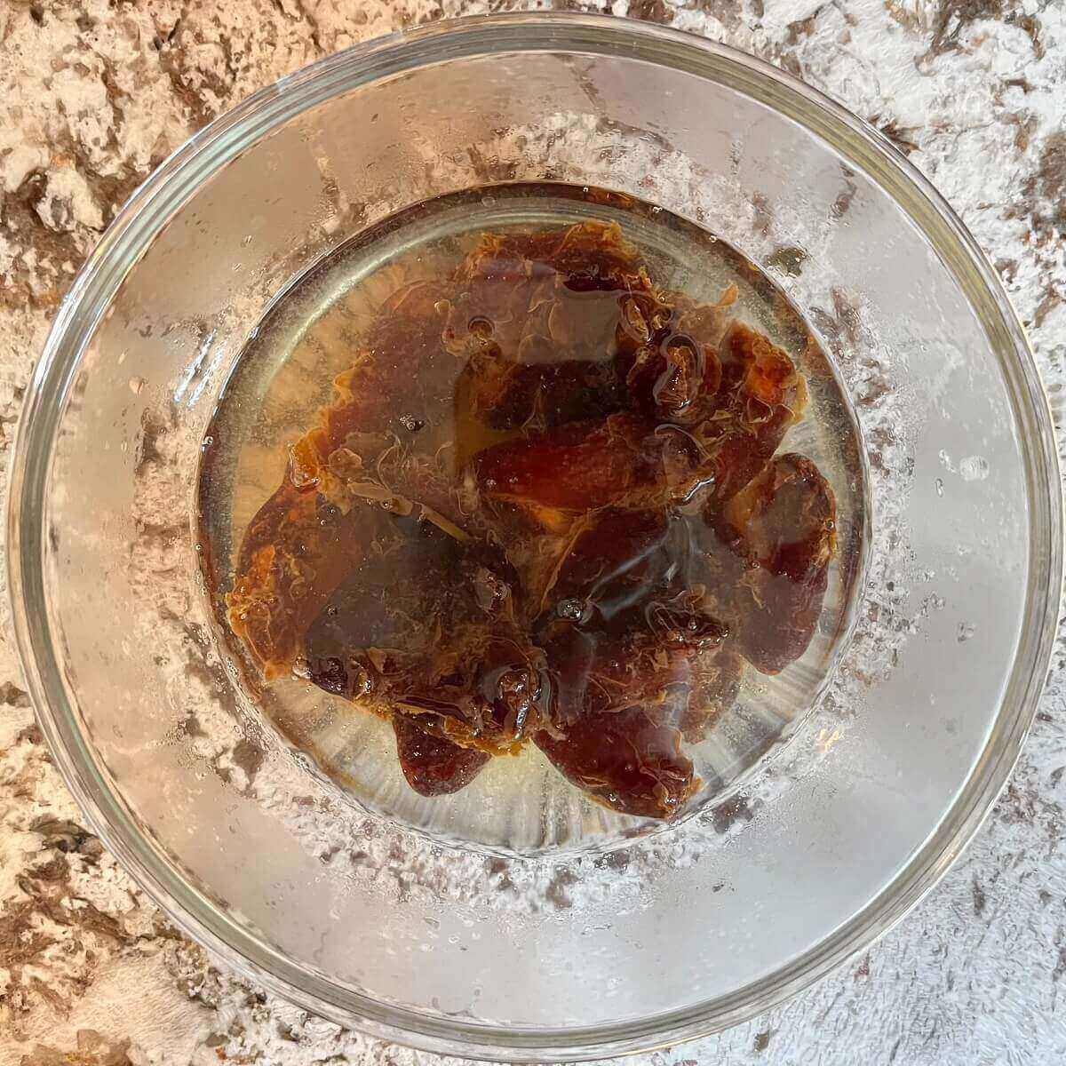 Dates soaking in hot water in a bowl.