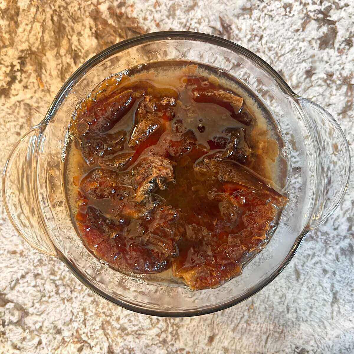 Dates soaking in boiling water in a glass bowl.