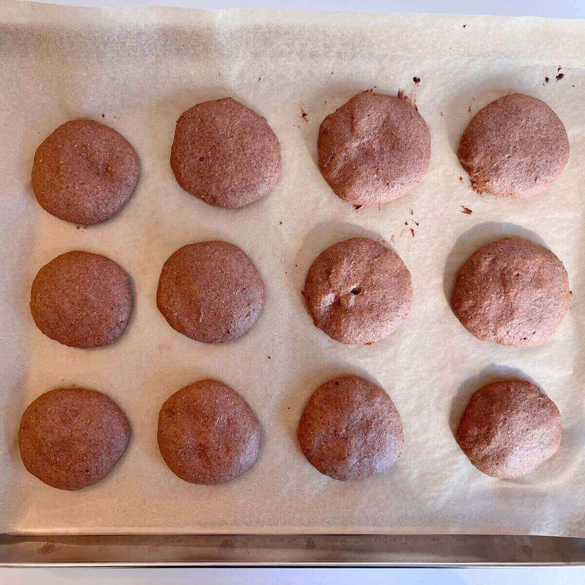 Freshly baked pink cookies on a sheet pan lined with parchment paper.