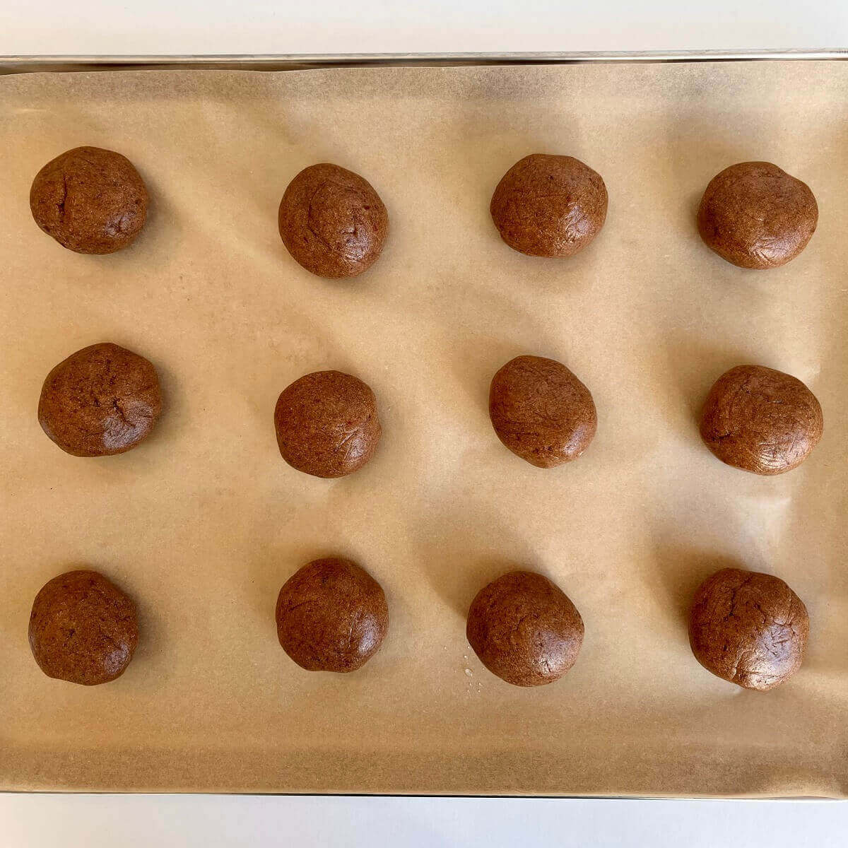 Raw amaranth dough balls on a parchment paper lined baking pan.