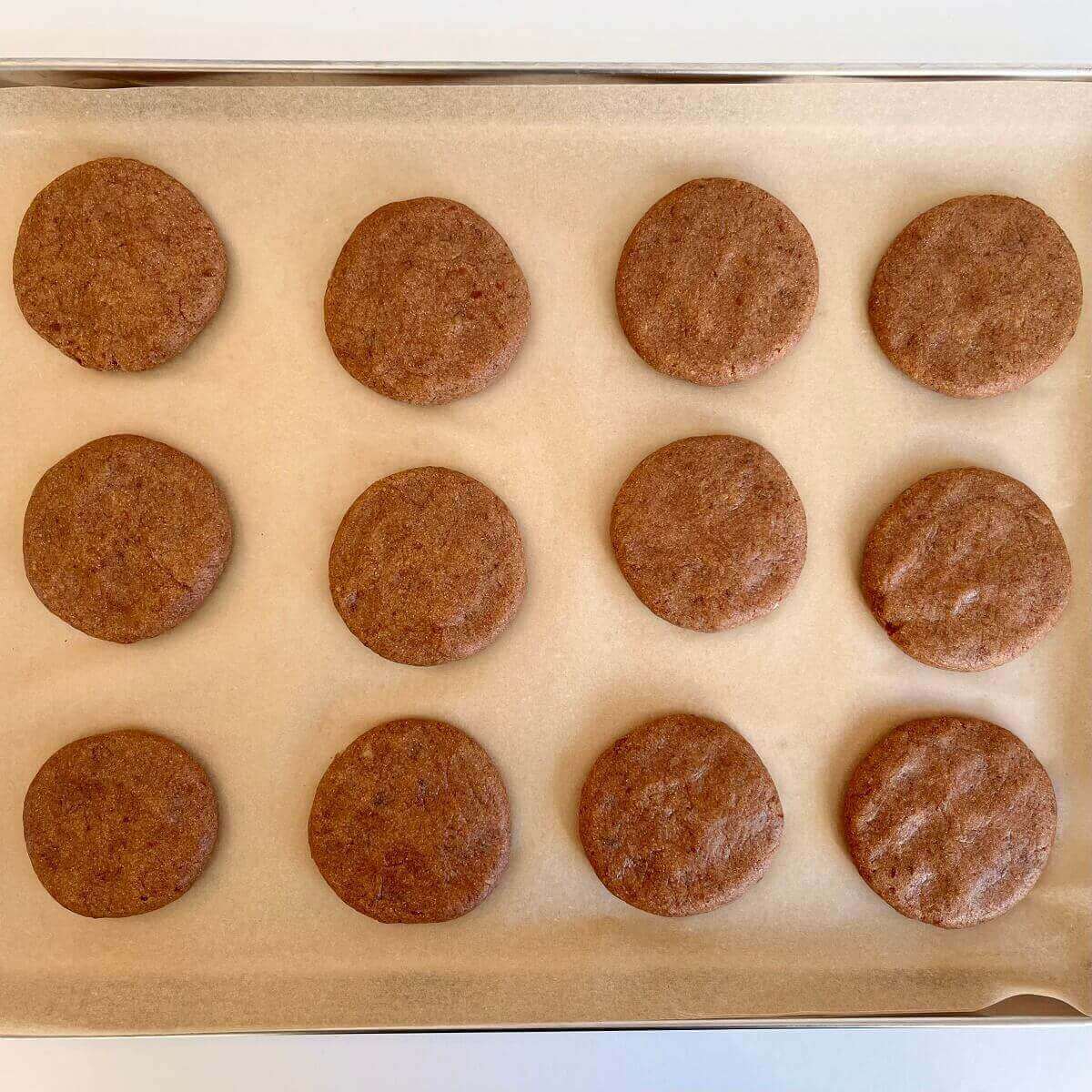 Raw beige cookies on a baking sheet lined with parchment paper.