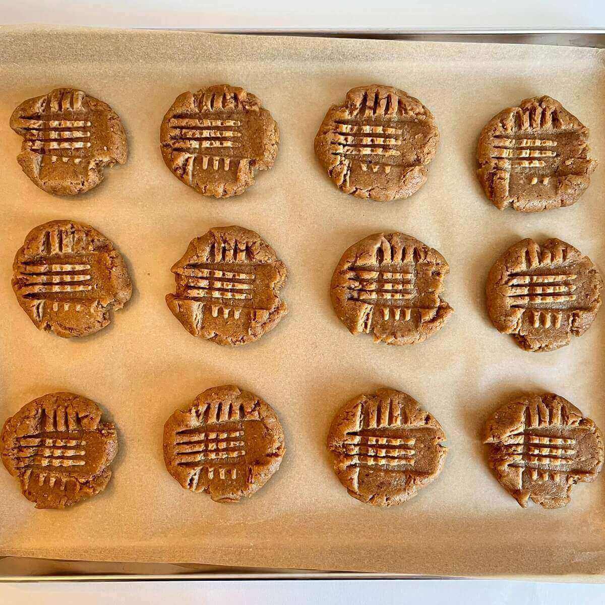 Raw peanut butter cookies on a sheet pan lined with parchment paper.