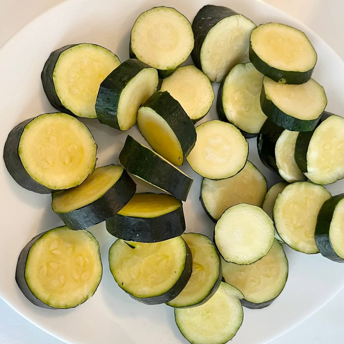 Raw zucchini slices on a white plate.