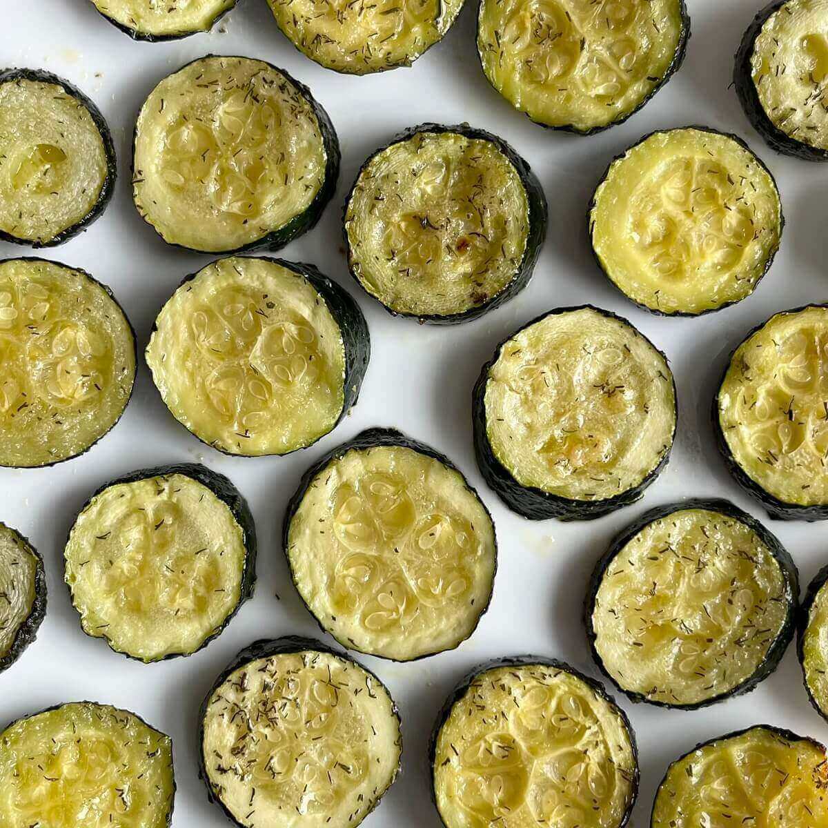 Cooked sliced zucchini on a white plate.