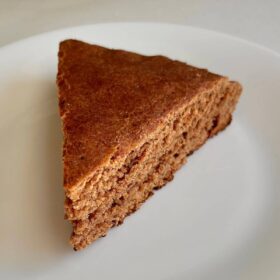 A slice of spelt flour cake on a white plate.