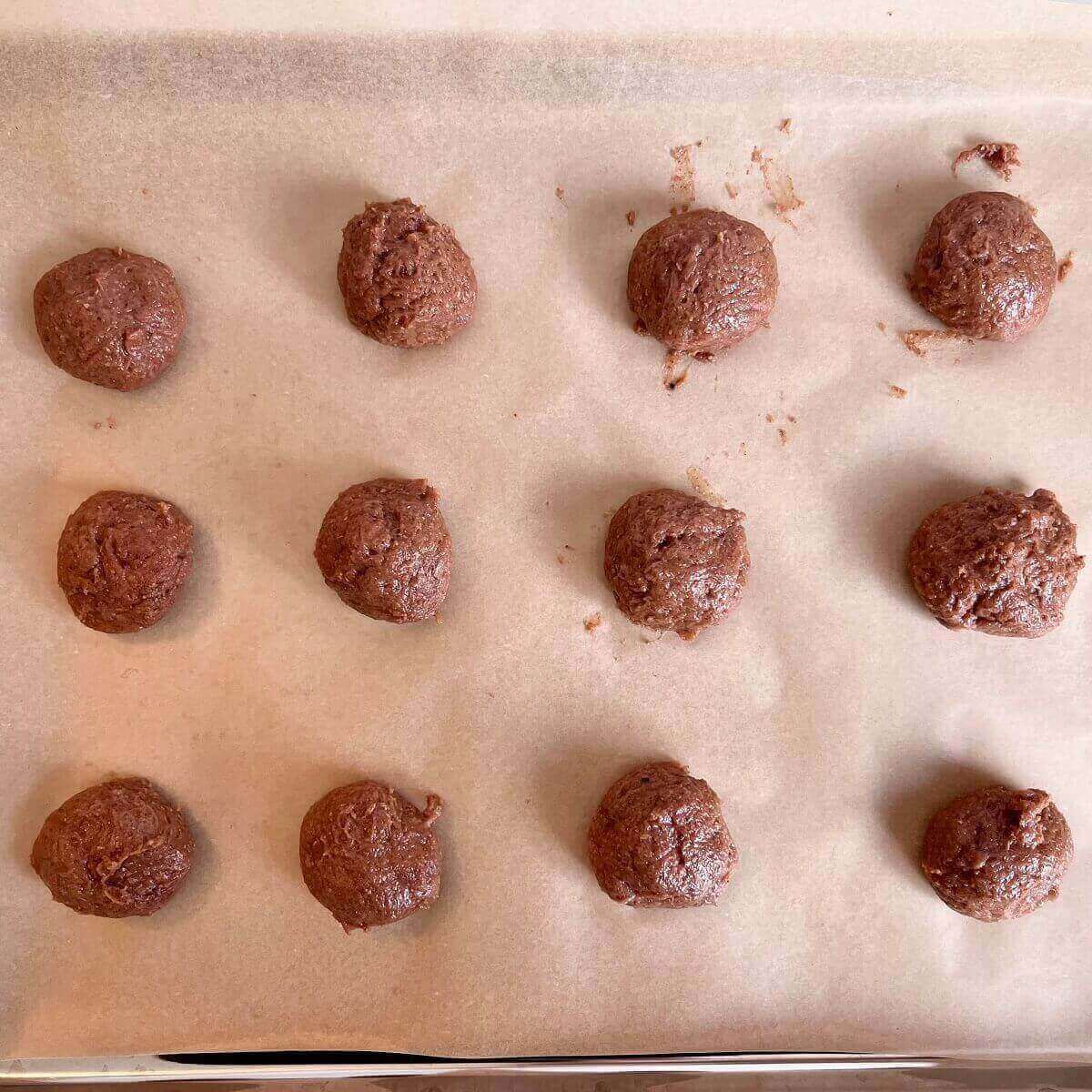 Strawberry dough balls on a sheet pan lined with parchment paper.