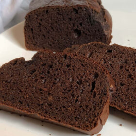 Brown bread on a white platter with two slices cut.