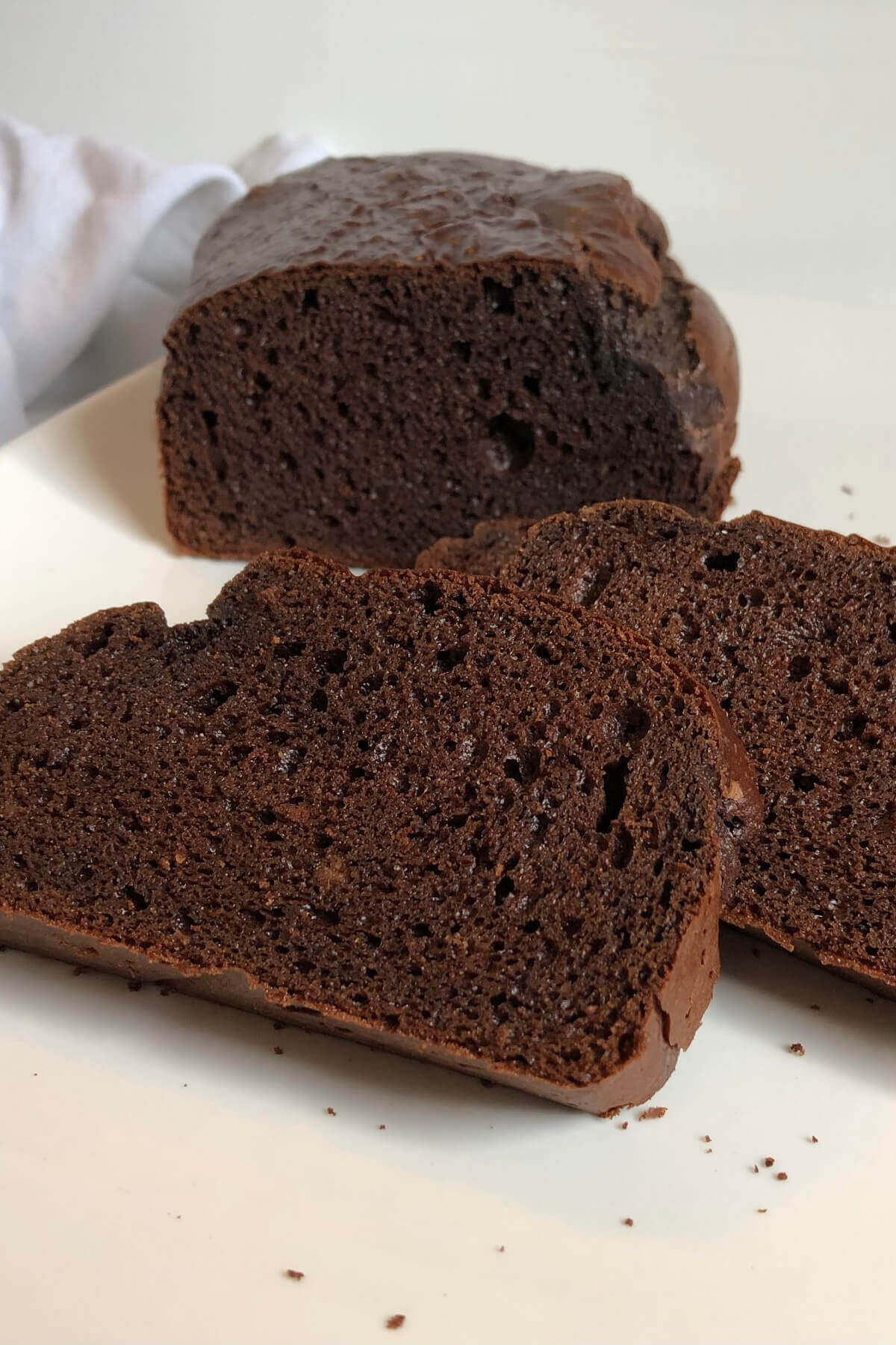 Brown bread on a white platter with two slices cut.