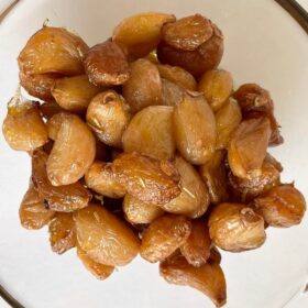 Cooked garlic cloves in a glass bowl.