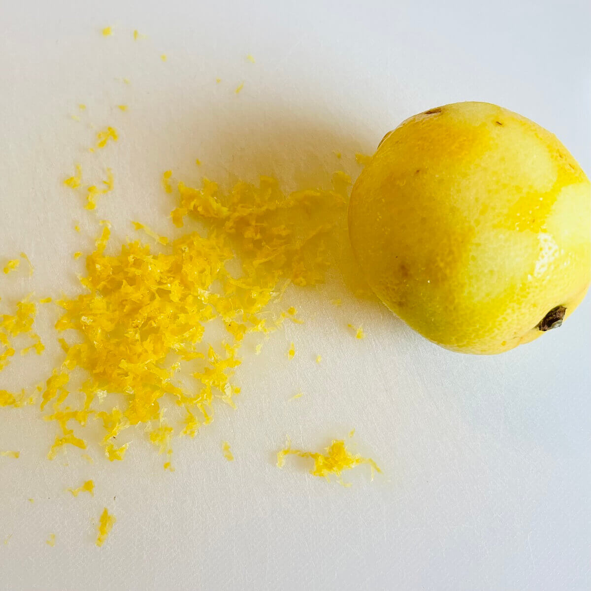 A lemon next to a pile of lemon zest.
