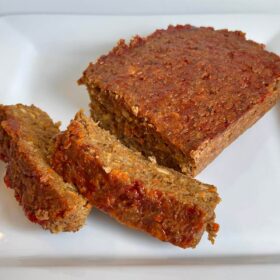 Vegetarian meatloaf on a white platter with two slices cut.