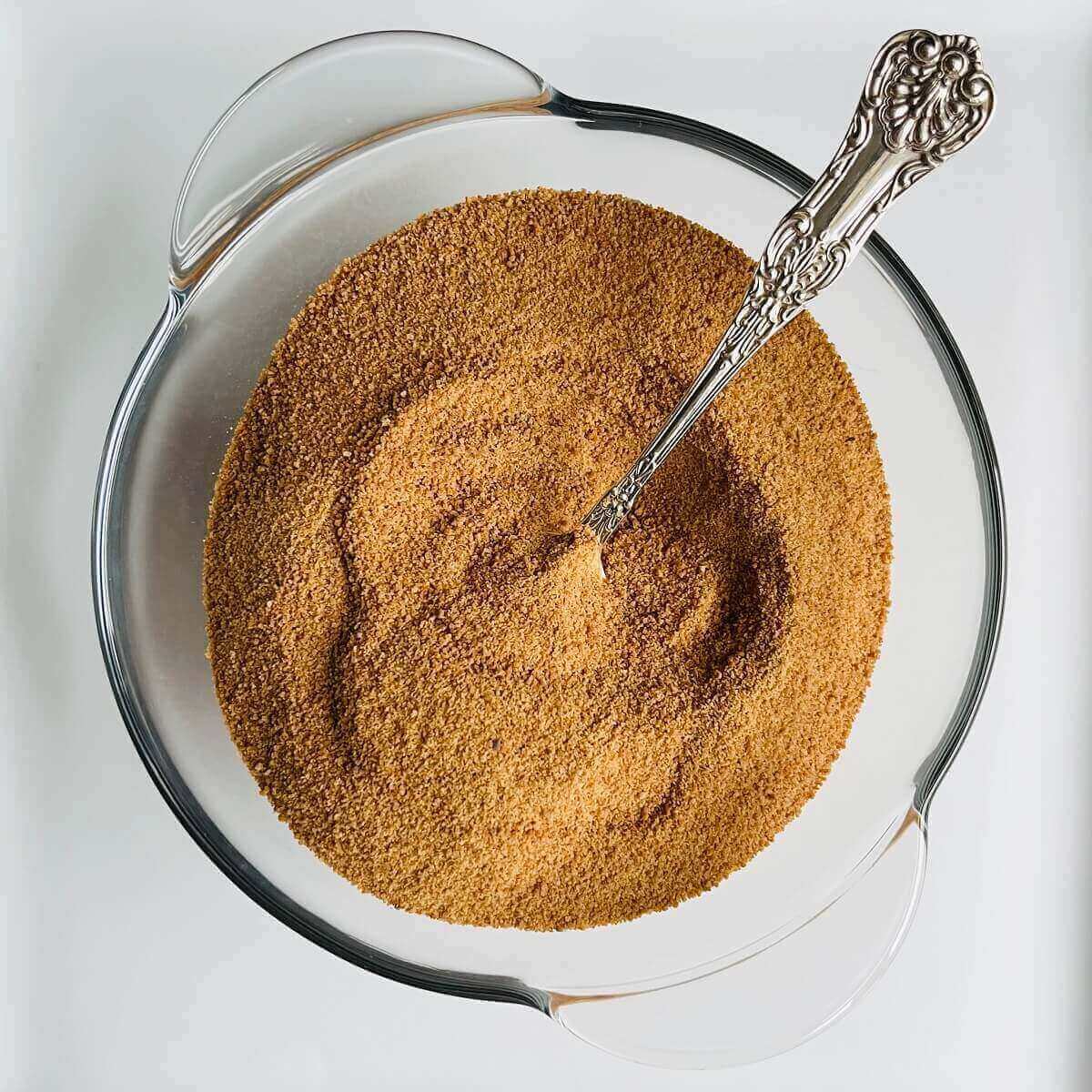 A glass bowl of coconut sugar with an antique silver spoon in it.