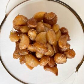 Cloves of roasted garlic confit in a glass bowl.