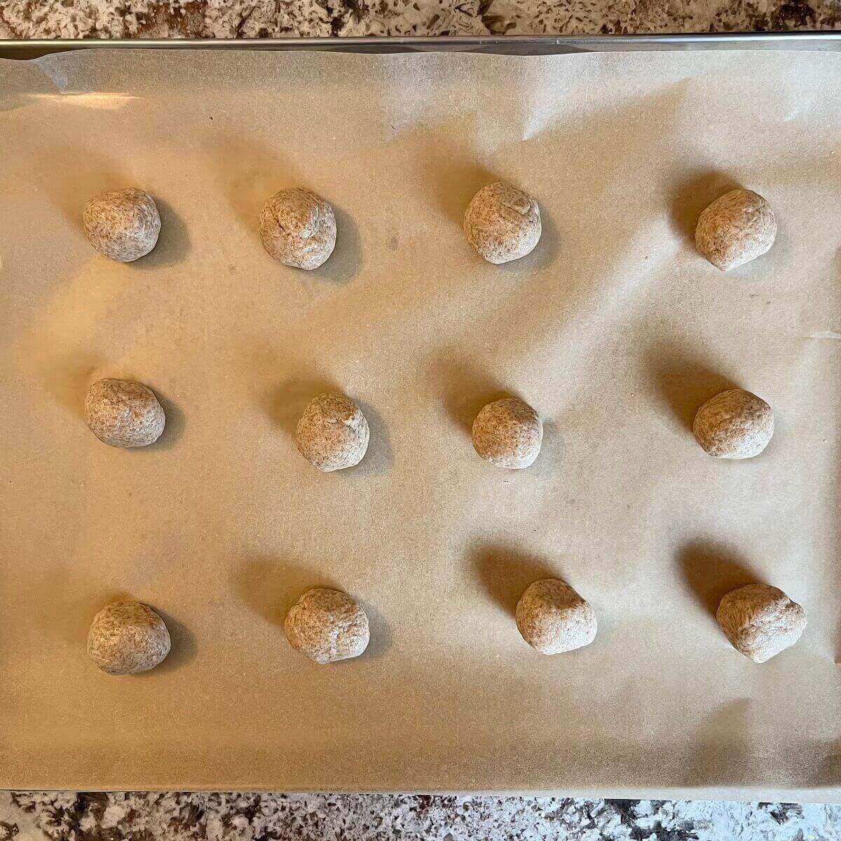 Spelt dough balls on a sheet pan lined with parchment paper.