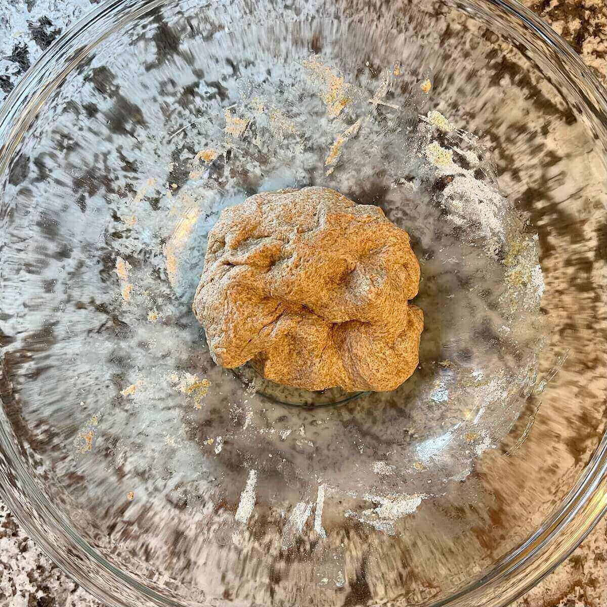 Spelt flour dough in a large glass mixing bowl.