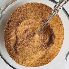 A bowl filled with coconut sugar with a silver spoon.