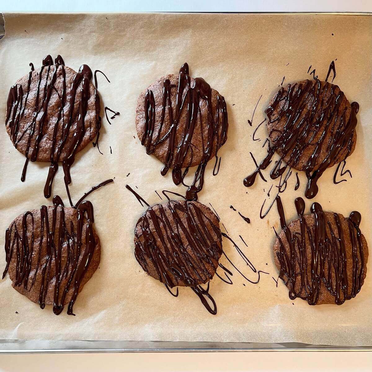 Chocolate drizzled flax cookies on a baking sheet.