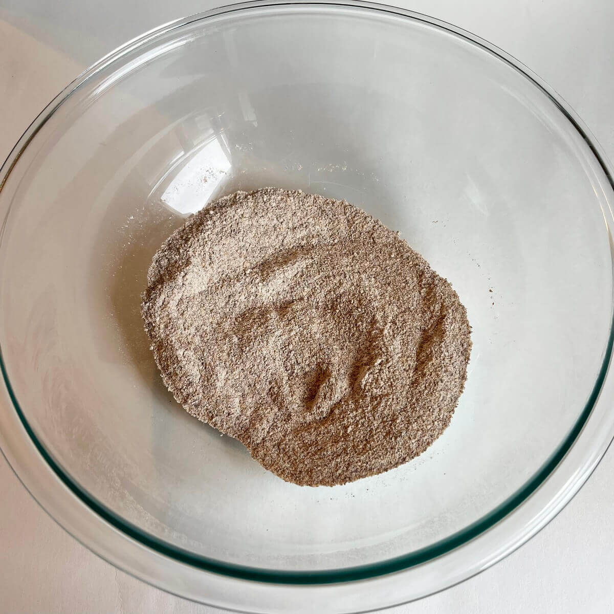 Ground flax, flour, and baking powder in a glass mixing bowl.